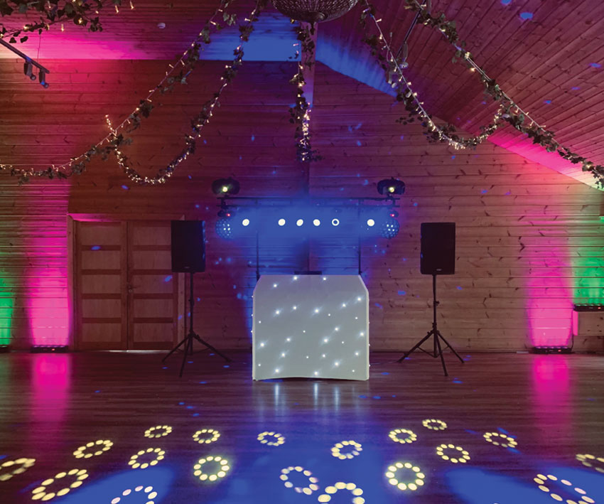 Large DJ setup with white lit booth and extra uplights